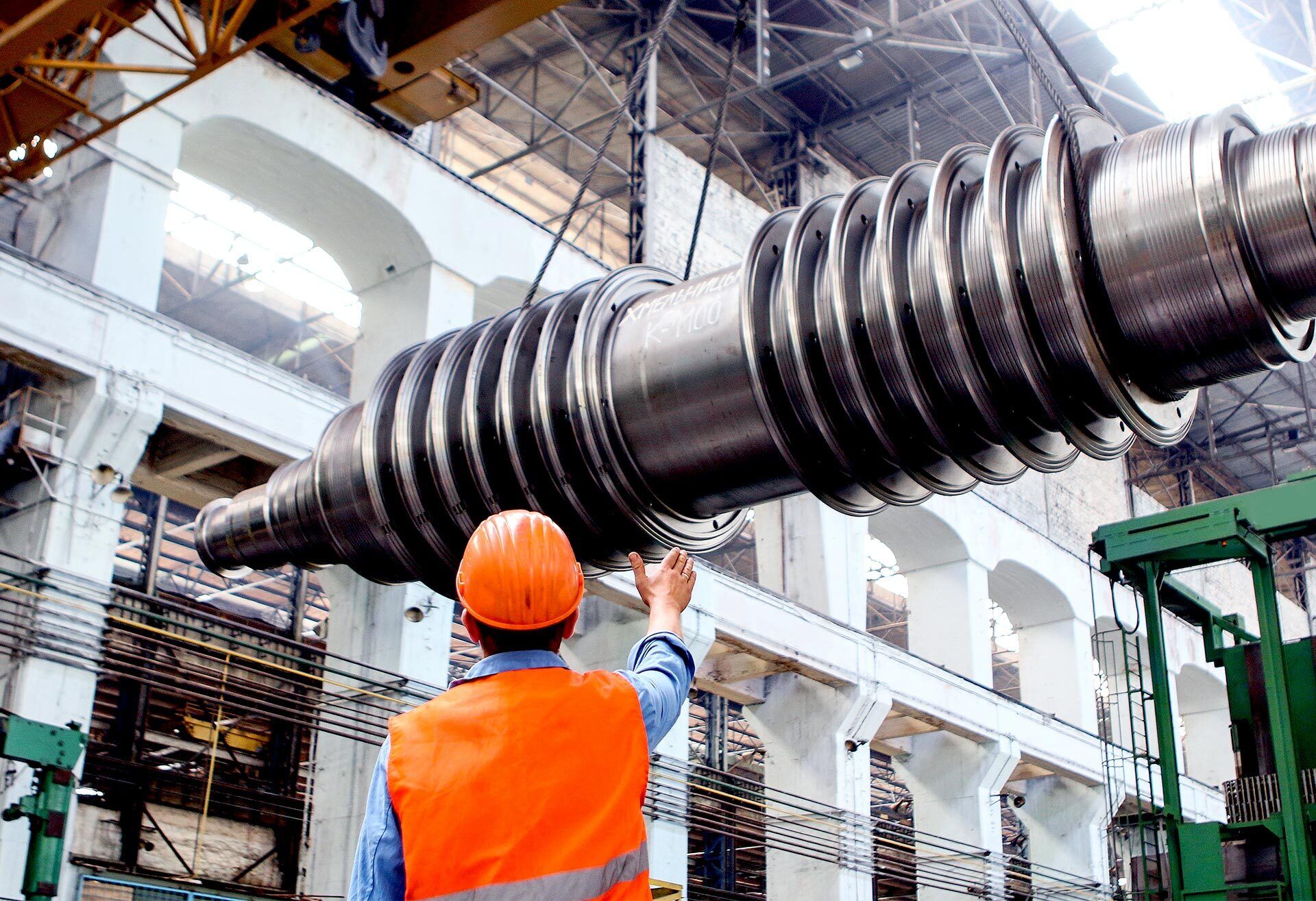 Mann mit Schutzhelm und grosses Metallteil Industriegebäude